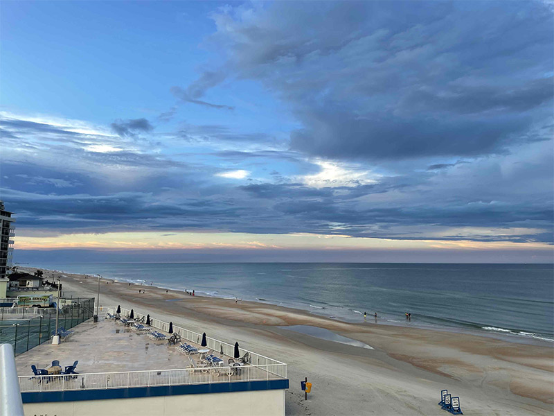 Sunset over the ocean with a view of the sand.,