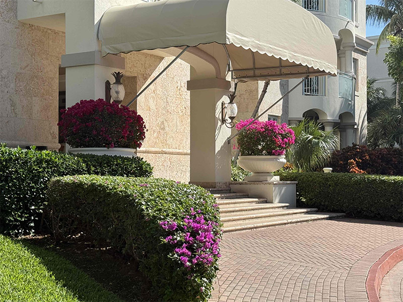 Entrance to the resort building, flanked by red and purple flowers in twin stone vases.