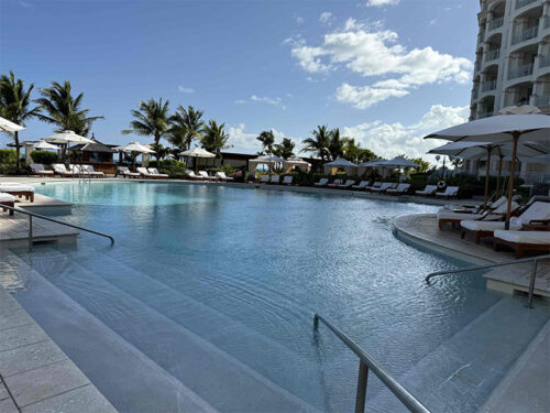 A wide, pale blue pool bordered by palms.