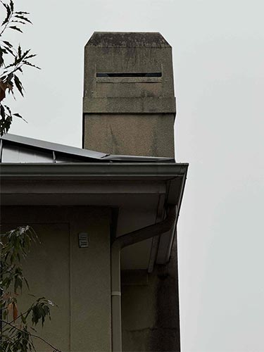 Picture of an old chimney stained with soot and with not to code vents.