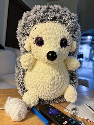 Picture of a crochet hedgehog with cure lavender eyes. 