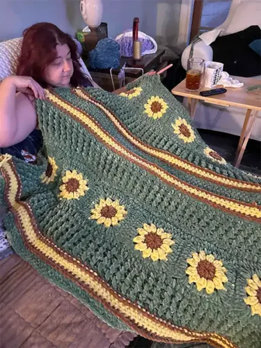 Candid shot of me from a weird angle with green blanket featuring sunflowers. 